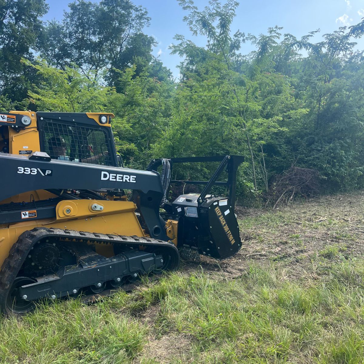 John Deere skidsteer and mulcher shown mulching trees in Paris, Texas